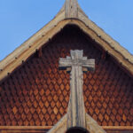 Träkors och tak på traditionell byggnad, bruna plankor, dekorativa mönster, blå himmel.