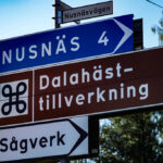 Vägskylt visar riktningar mot Nusnäs, dalahästtillverkning, och sågverk.