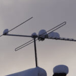 TV-antenn täckt med snö mot mulen himmel
