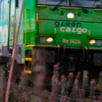 Grönt godståg "Green Cargo" Re 1424 i rörelse på spår med vegetation runtom.
