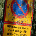Gammal parkeringsförbudsskylt från Göteborg med kontaktinfo, täckt av mossa.